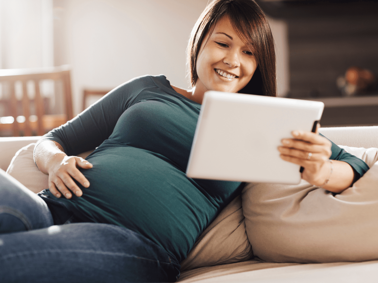 Mujer embarazada relajada usando una tablet, representando claridad y tranquilidad sobre su postparto y lactancia.