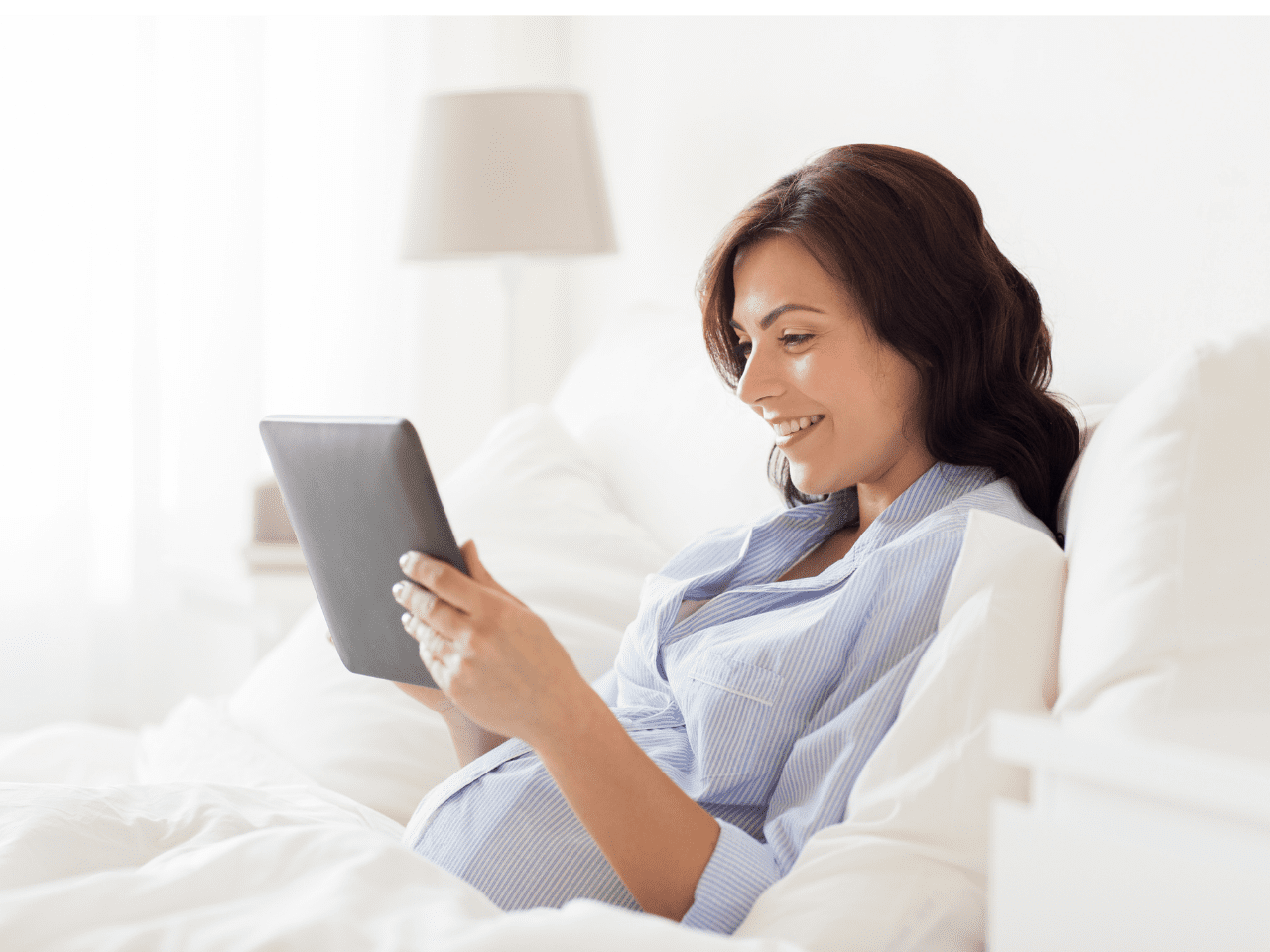 Mujer embarazada sonriendo mientras ve información en su tablet, representando la claridad y calma que ofrece el curso.