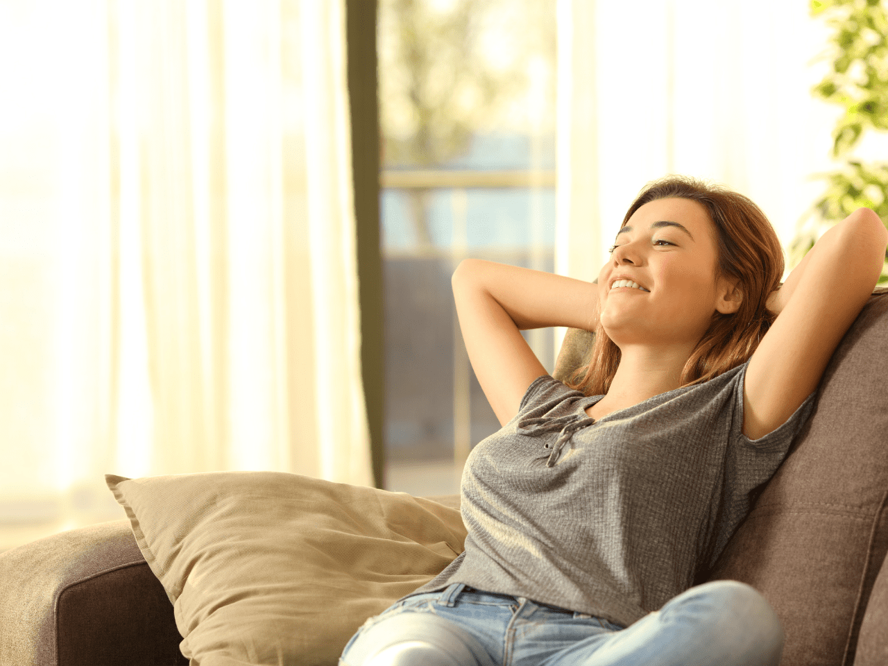 Mujer sonriendo con calma en un ambiente cálido, representando el bienestar realista que se busca alcanzar con el curso Nutriendo tu Bienestar.