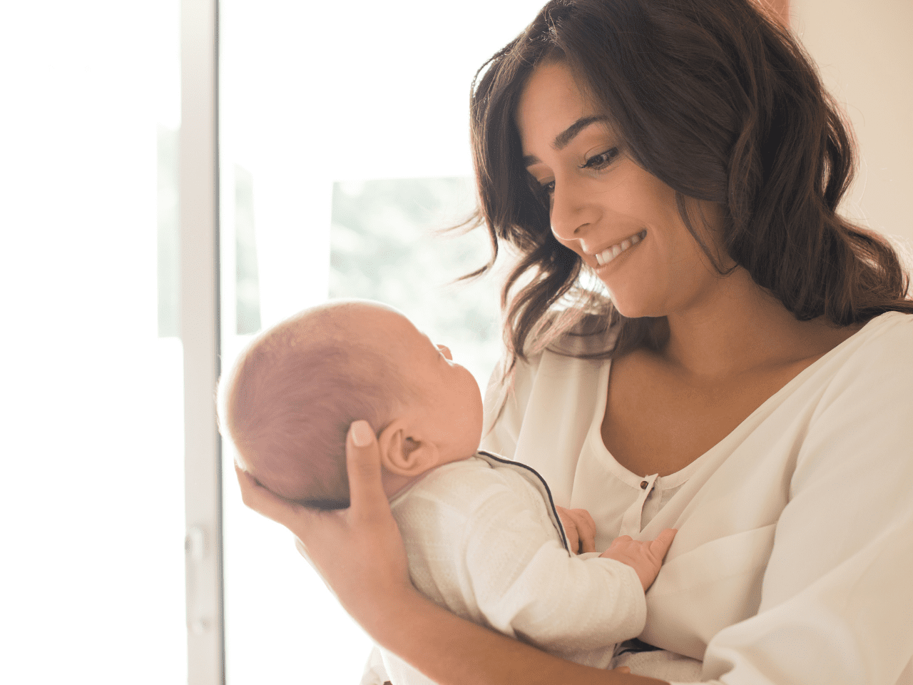 Mamá en postparto sosteniendo a su bebé con expresión de calma y bienestar, representando la recuperación y claridad que ofrece el curso Nutre tu Postparto.