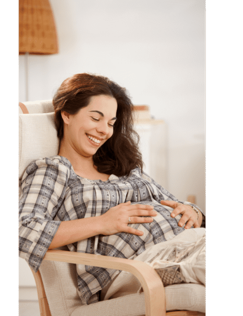 Mujer embarazada sentada y tranquila, sonriendo con calma, representando seguridad y claridad en su alimentación durante el embarazo.